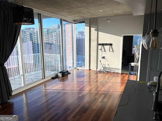 interior space with arched walkways, a view of city, wood finished floors, and floor to ceiling windows