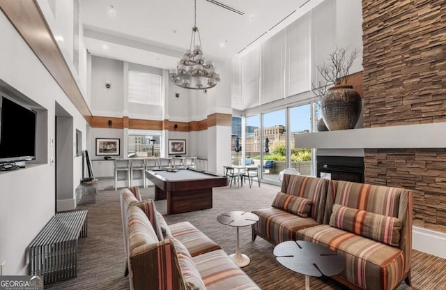 interior space featuring pool table, a high ceiling, carpet flooring, a chandelier, and a multi sided fireplace