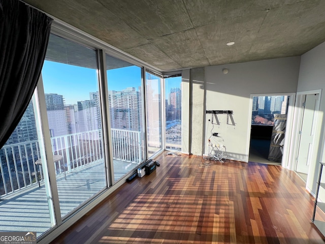 interior space with a view of city, expansive windows, and wood finished floors