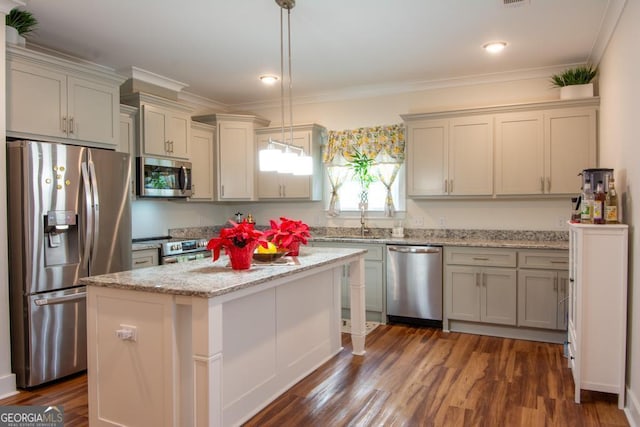 kitchen featuring pendant lighting, a center island, dark wood-type flooring, ornamental molding, and stainless steel appliances