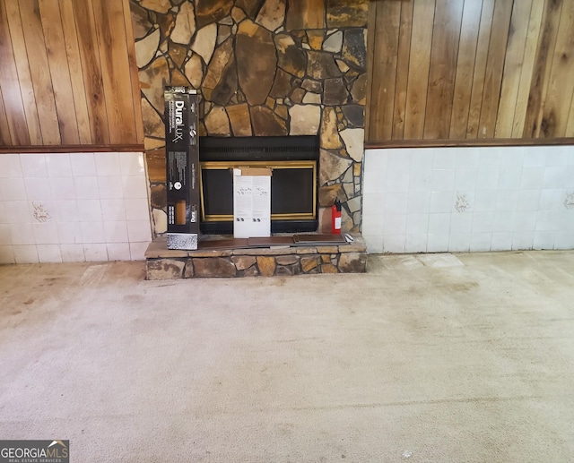 details with a stone fireplace, carpet floors, and wooden walls