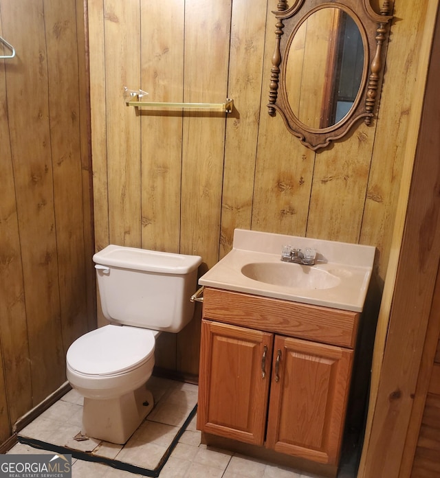 bathroom with wooden walls, tile patterned flooring, vanity, and toilet