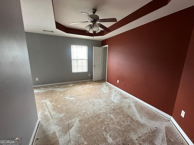 empty room featuring a tray ceiling and ceiling fan