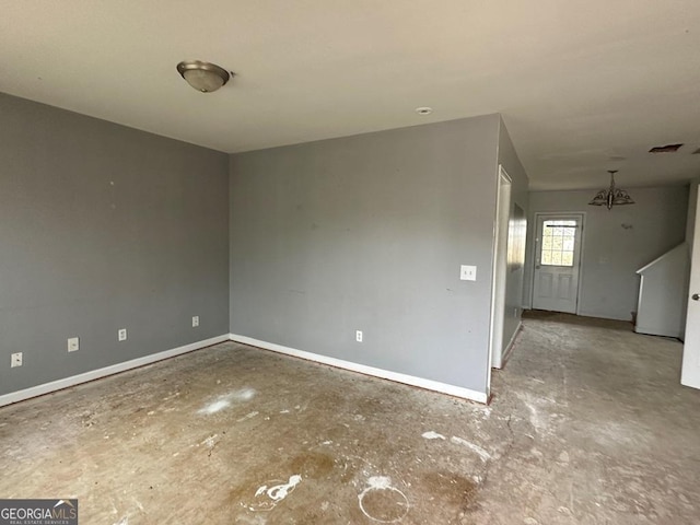 unfurnished room featuring a chandelier