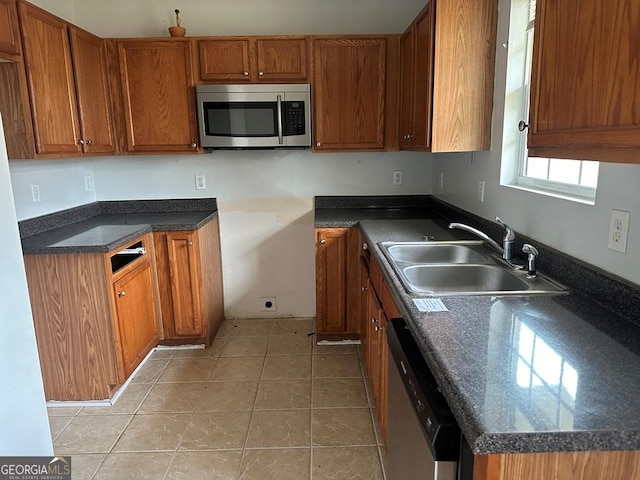 kitchen with appliances with stainless steel finishes, light tile patterned floors, and sink