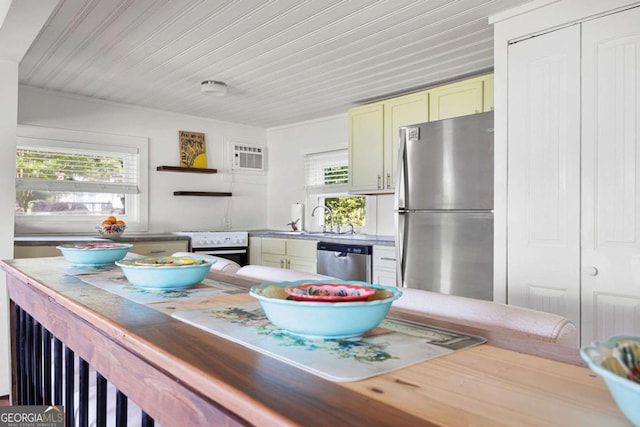 kitchen with a wall mounted air conditioner, green cabinets, sink, and stainless steel appliances