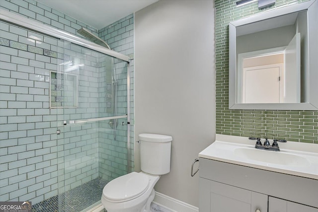 bathroom featuring tasteful backsplash, vanity, a shower with shower door, and toilet