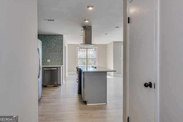 kitchen with decorative backsplash, appliances with stainless steel finishes, light wood-type flooring, ventilation hood, and a center island