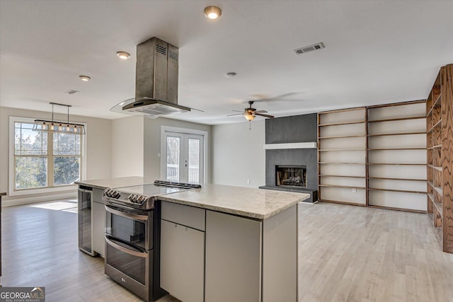 kitchen with island exhaust hood, stainless steel electric range oven, plenty of natural light, and hanging light fixtures