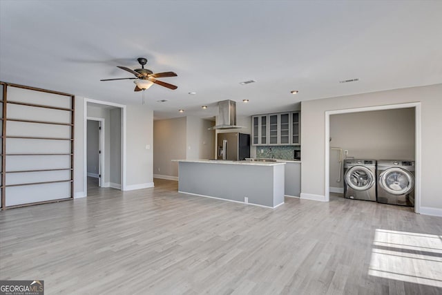 unfurnished living room featuring ceiling fan, independent washer and dryer, and light hardwood / wood-style flooring