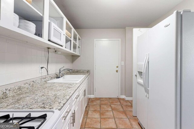 kitchen featuring white cabinetry, white fridge with ice dispenser, light stone countertops, sink, and tasteful backsplash