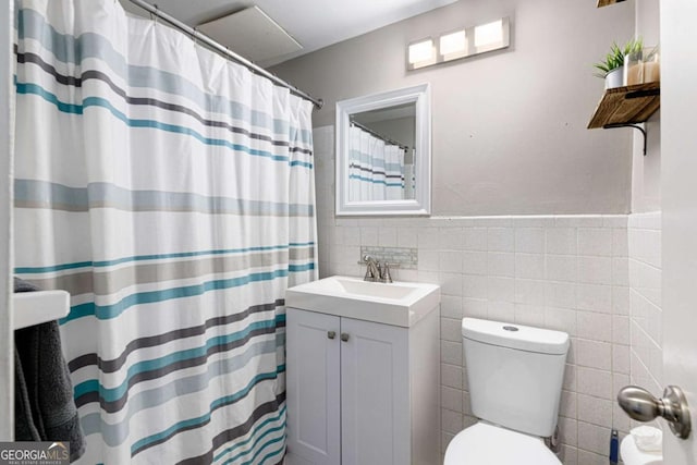 bathroom with curtained shower, vanity, tile walls, and toilet