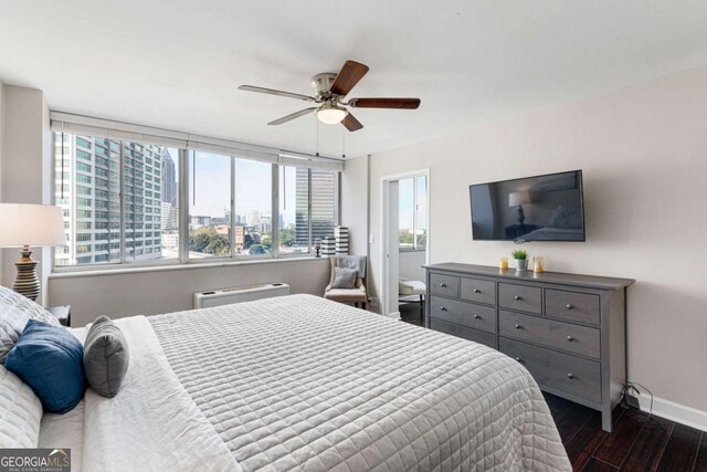 bedroom featuring multiple windows, ceiling fan, dark hardwood / wood-style flooring, and a wall mounted air conditioner