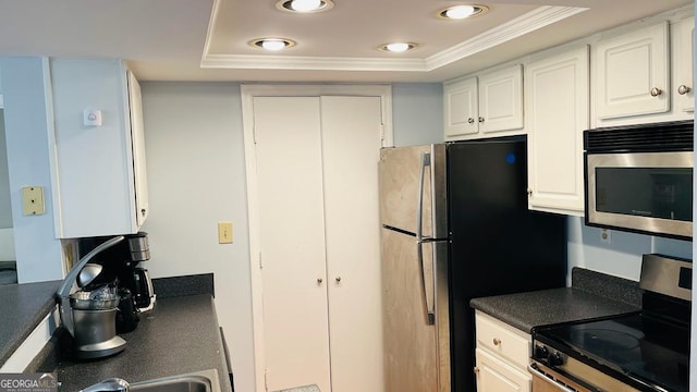 kitchen featuring crown molding, white cabinetry, stainless steel appliances, and a tray ceiling