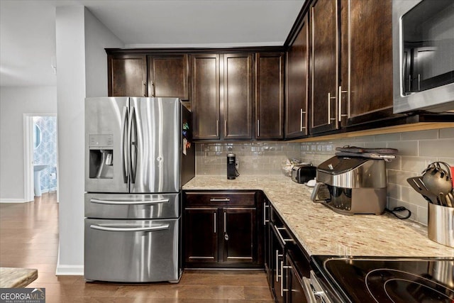 kitchen with appliances with stainless steel finishes, backsplash, and dark brown cabinetry