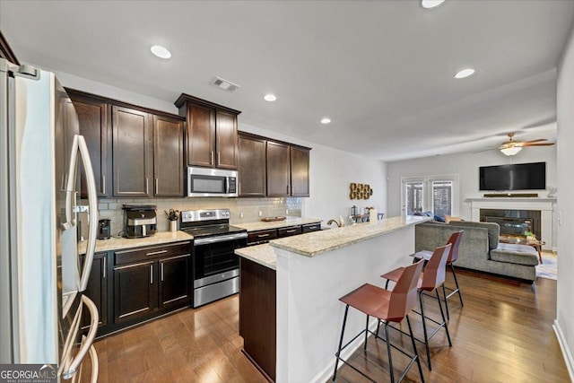 kitchen featuring a breakfast bar area, appliances with stainless steel finishes, ceiling fan, backsplash, and a kitchen island