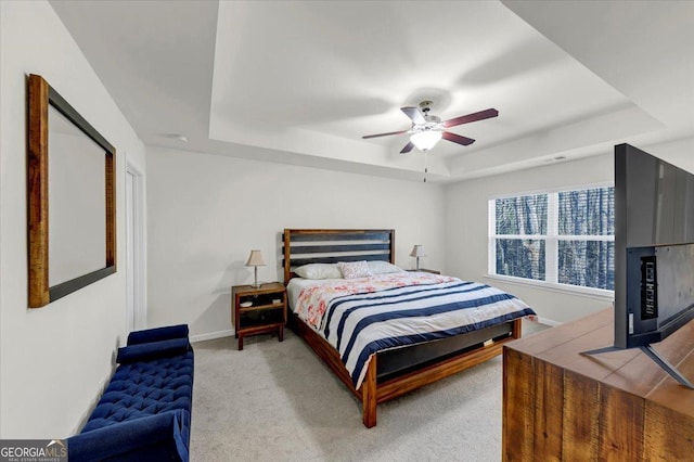 bedroom with ceiling fan, a tray ceiling, and carpet flooring