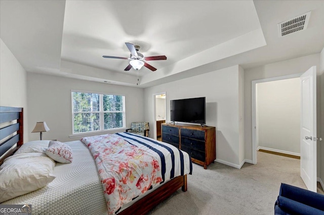 carpeted bedroom with ceiling fan and a tray ceiling