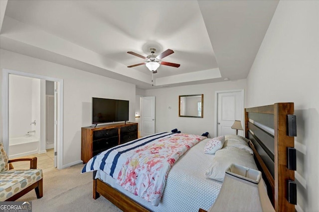 carpeted bedroom featuring a raised ceiling, ceiling fan, and ensuite bathroom