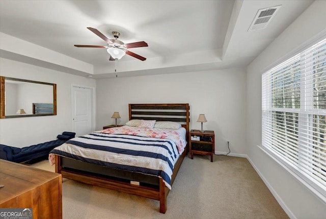 carpeted bedroom featuring ceiling fan and a tray ceiling