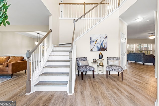 stairs with hardwood / wood-style floors and crown molding