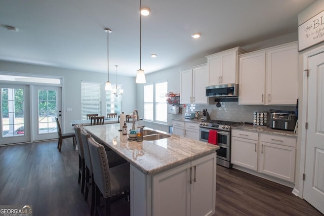 kitchen with white cabinetry, sink, hanging light fixtures, stainless steel appliances, and a kitchen island with sink