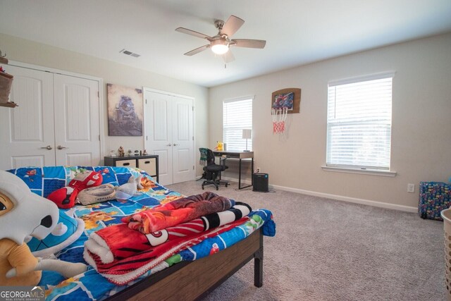 bedroom featuring ceiling fan, light colored carpet, and multiple windows