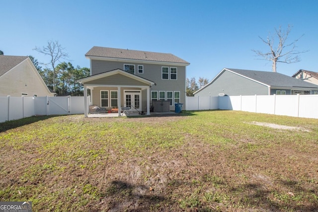 back of house featuring french doors, a patio area, and a lawn