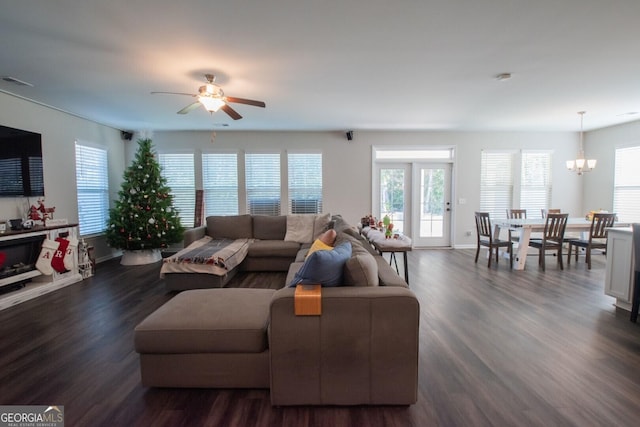 living room with dark wood-type flooring and ceiling fan with notable chandelier