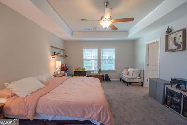 carpeted bedroom with a tray ceiling, ceiling fan, and crown molding