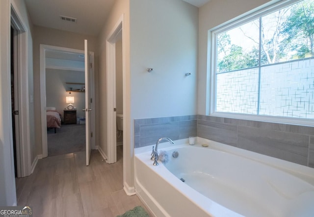 bathroom featuring toilet and a tub to relax in