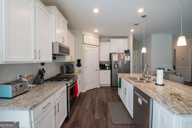 kitchen with dark wood-type flooring, a center island with sink, hanging light fixtures, white cabinetry, and stainless steel appliances