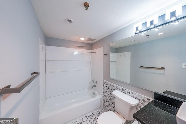 bathroom featuring tiled shower / bath combo, toilet, and tile walls