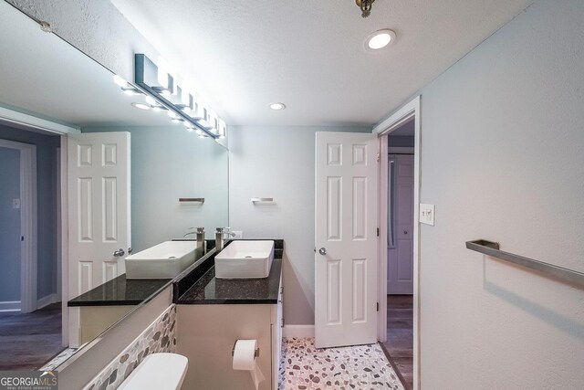 bathroom featuring hardwood / wood-style floors, vanity, a textured ceiling, and toilet