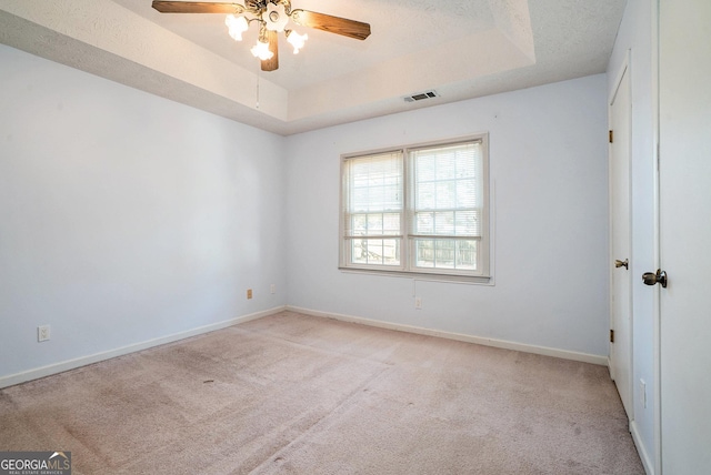 carpeted spare room with ceiling fan, a raised ceiling, and a textured ceiling