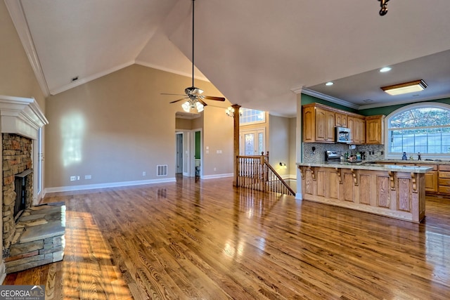 kitchen with wood-type flooring, backsplash, ornamental molding, and vaulted ceiling