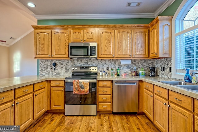 kitchen featuring tasteful backsplash, appliances with stainless steel finishes, crown molding, and light hardwood / wood-style floors