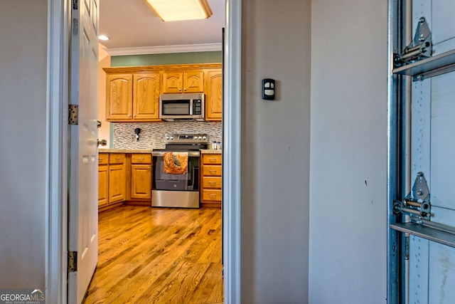 kitchen with tasteful backsplash, crown molding, stainless steel appliances, and light hardwood / wood-style floors