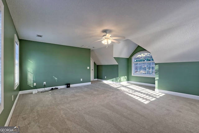 bonus room featuring a textured ceiling, ceiling fan, carpet, and vaulted ceiling