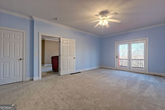 carpeted spare room with ceiling fan, ornamental molding, and french doors