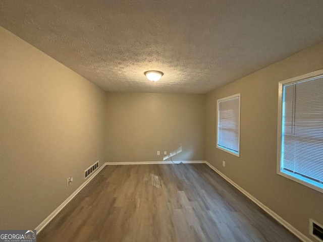 unfurnished room featuring wood-type flooring and a textured ceiling