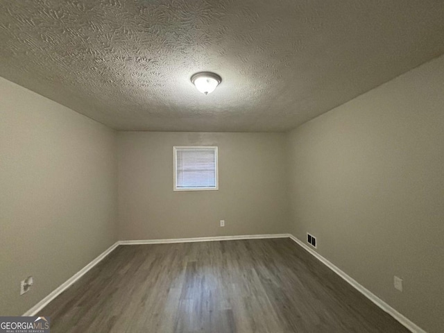 unfurnished room featuring a textured ceiling and dark wood-type flooring