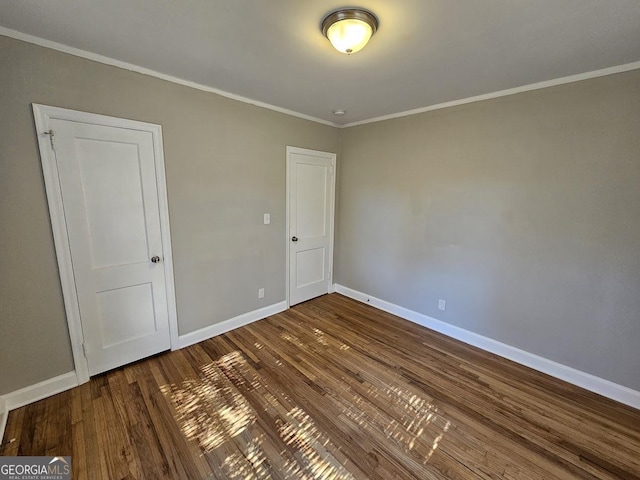 empty room featuring wood-type flooring and crown molding