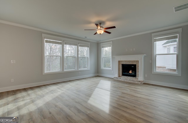 unfurnished living room with a wealth of natural light, light hardwood / wood-style flooring, ceiling fan, and ornamental molding