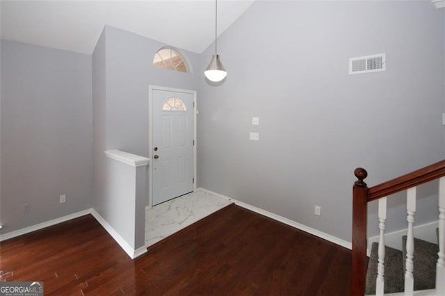 foyer entrance with dark hardwood / wood-style flooring and high vaulted ceiling