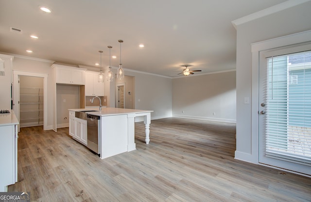 kitchen featuring sink, stainless steel dishwasher, an island with sink, decorative light fixtures, and white cabinetry