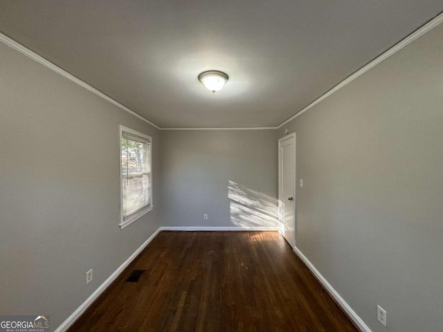 spare room with crown molding and dark wood-type flooring