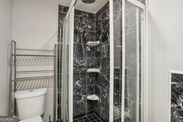 bathroom featuring toilet and a shower with shower door