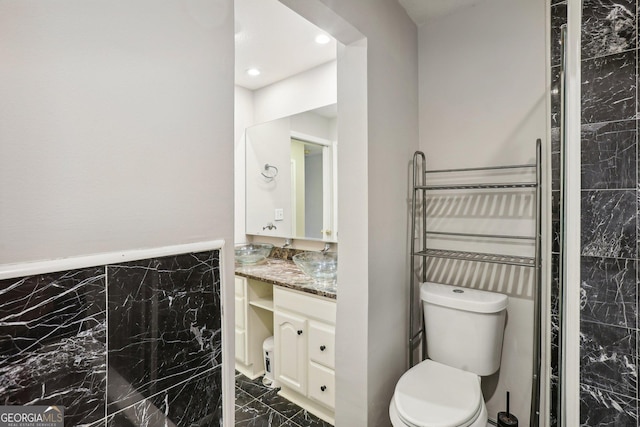 bathroom featuring vanity, tile walls, and toilet