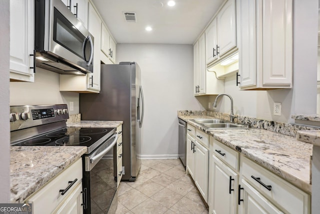 kitchen featuring light stone countertops, appliances with stainless steel finishes, sink, light tile patterned floors, and white cabinets